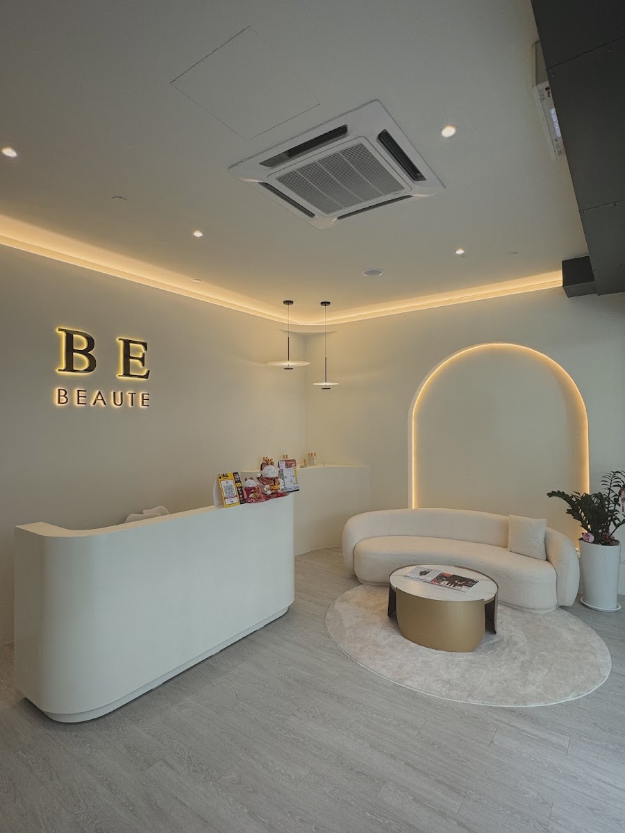 The Be Beaute reception at Plaza Arkadia, with the gold BE BEAUTE sign and a curved boucle sofa