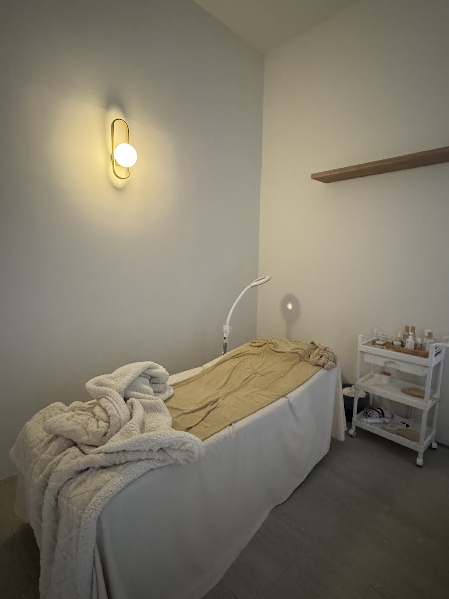 A private Be Beaute treatment room with a warm gold wall light and prepared treatment bed